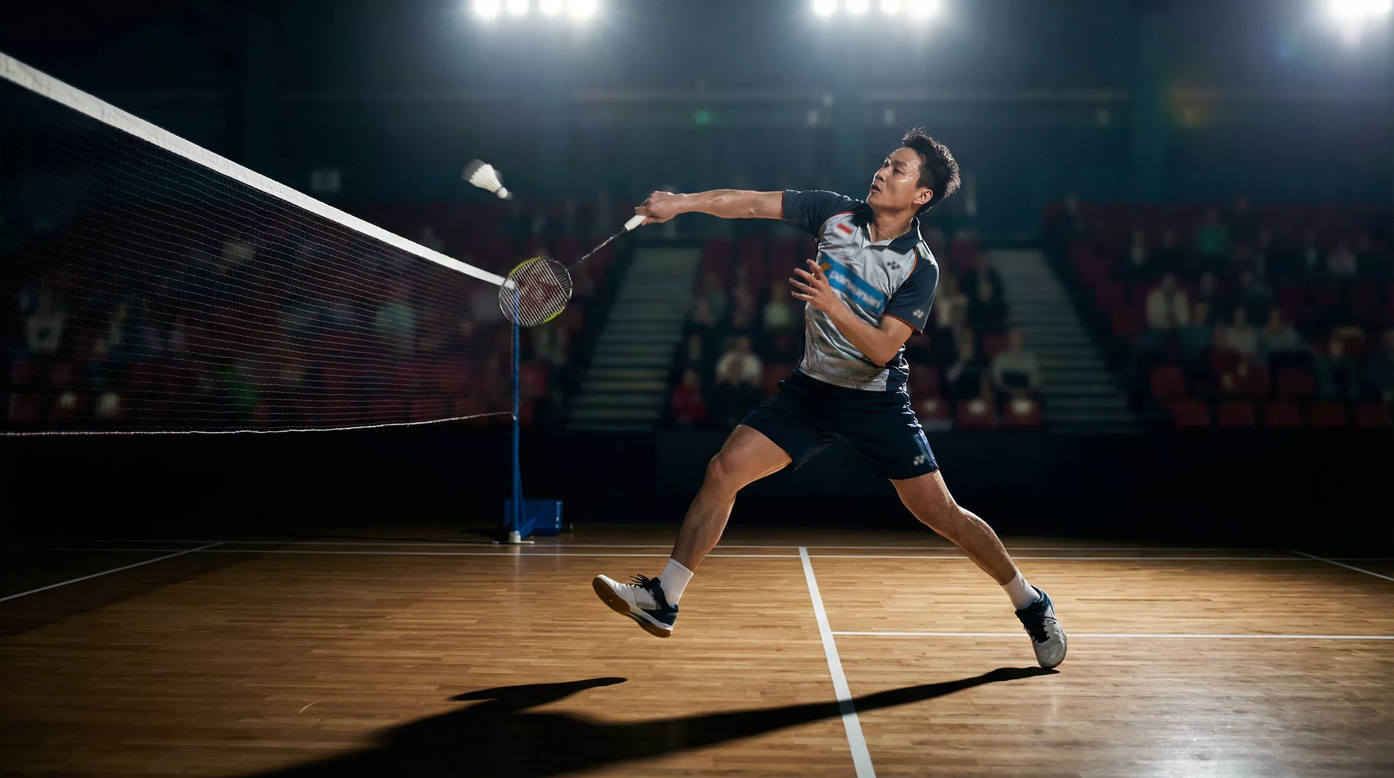 Badminton-Spieler schlägt Federball am Netz bei einem Turniermatch