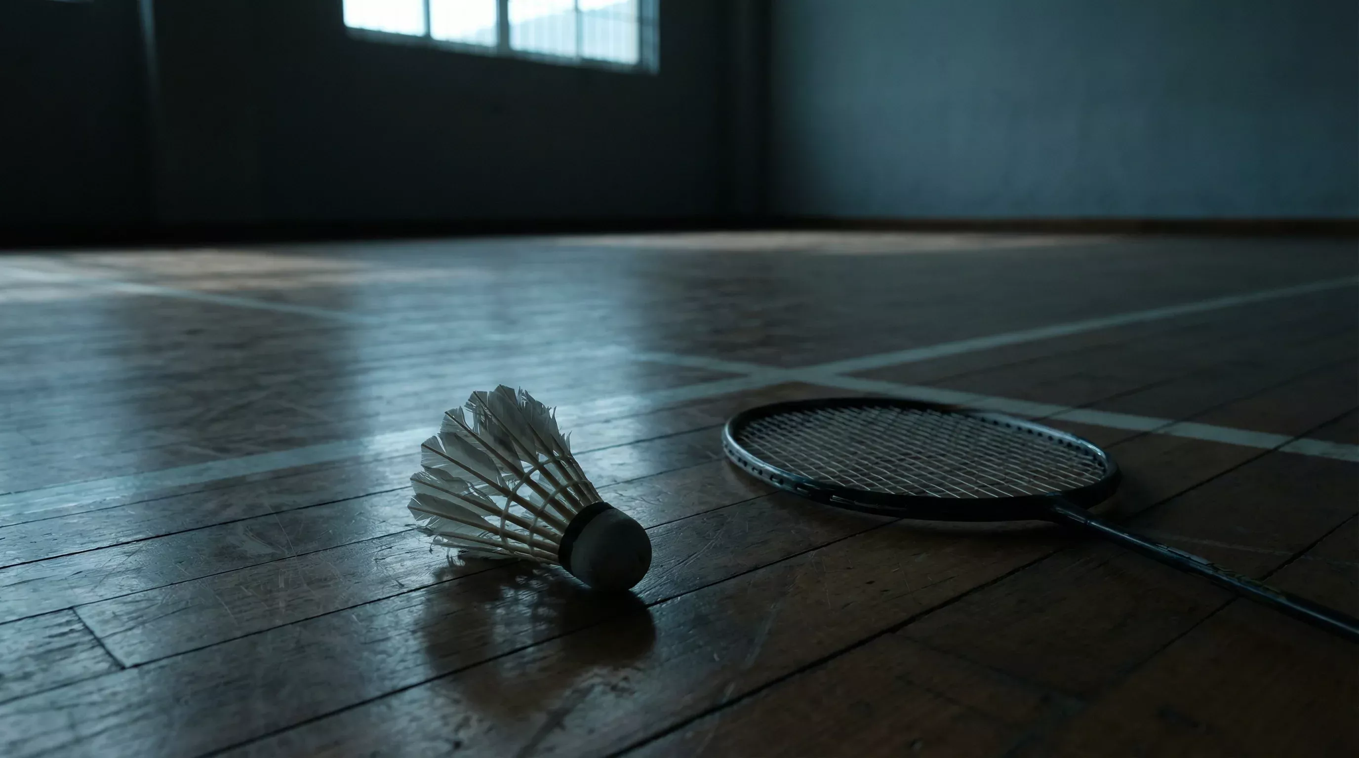 Zerbrochener Badminton-Federball neben einem Schläger auf dem Spielfeld